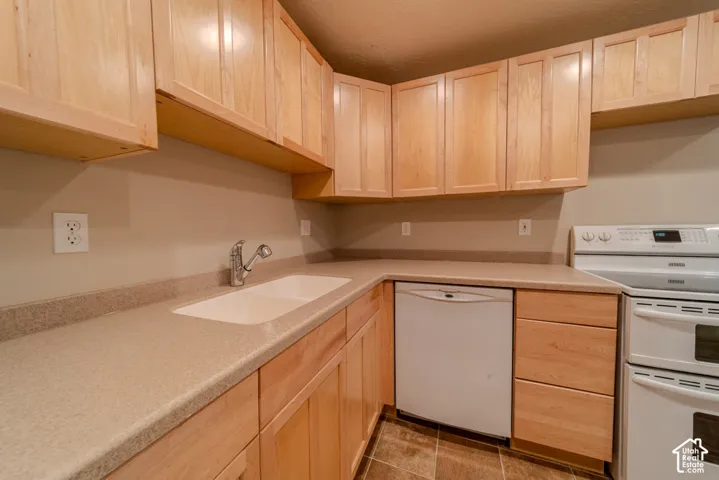 Kitchen featuring wood cabinetry, laminate countertops, a double basin sink with chrome faucet, an electric range, and a dishwasher