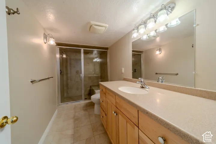 Spacious bathroom featuring a light wood-finish vanity with ample storage, a large countertop, and an integrated sink