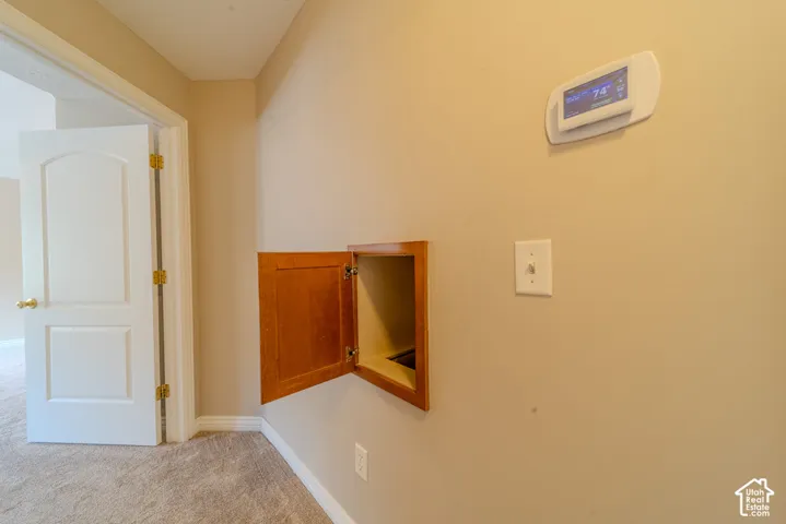 Wall-mounted wooden cabinet with an open door, a digital thermostat, and a light switch against a neutral painted wall