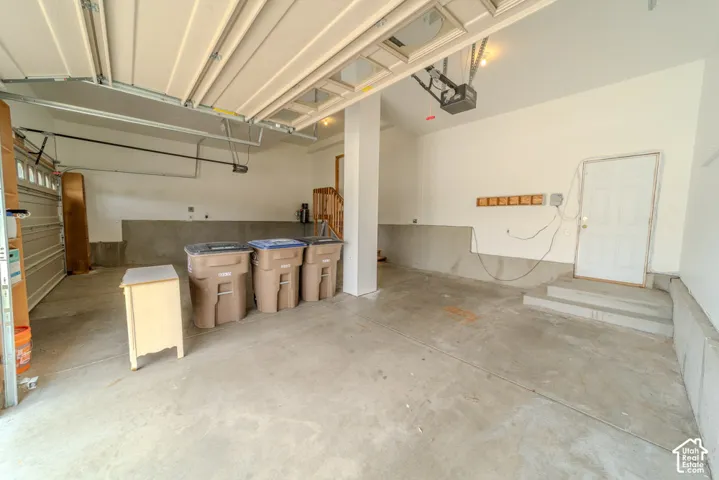 Spacious garage with light-toned walls, concrete flooring, and an overhead garage door mechanism