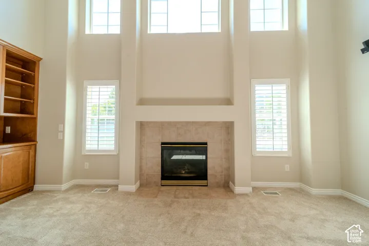 Soaring two-story ceilings frame a central fireplace with a tile surround and hearth