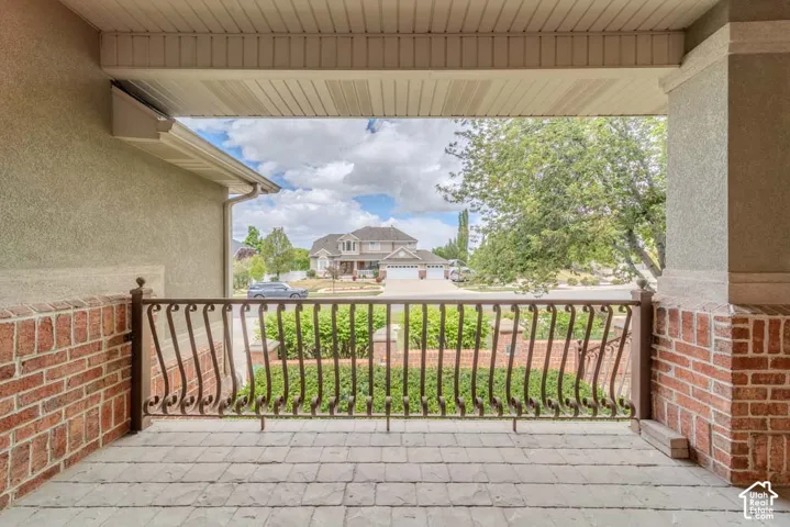 Covered patio featuring a wrought iron railing, brick accents, and stamped concrete flooring