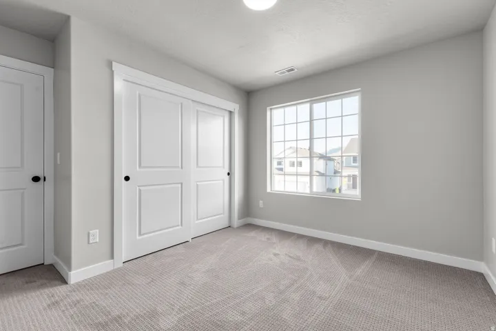 Room featuring light gray carpet, white trim, and a four-panel sliding closet door