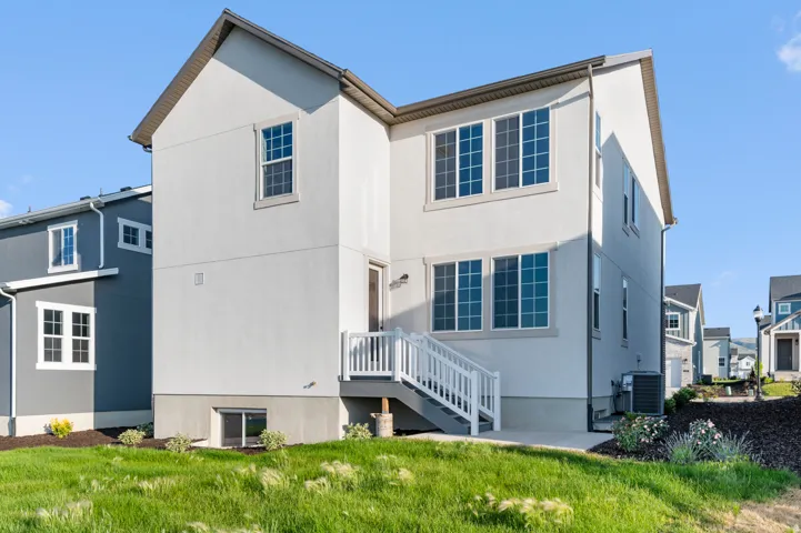 Rear exterior featuring a light stucco finish and multiple windows with white trim