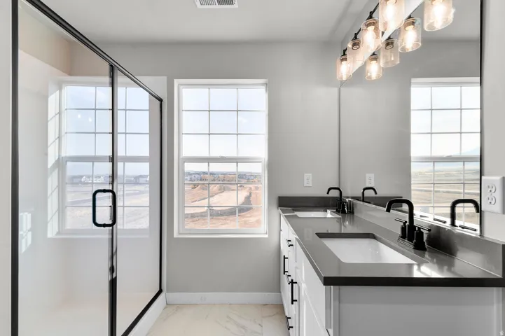 Bathroom featuring a dual vanity with undermount sinks, dark countertops, and matte black fixtures