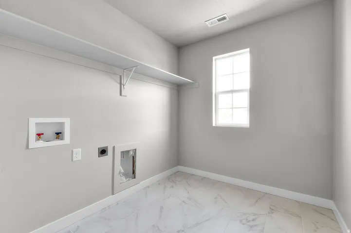 Utility room featuring marble-look tile flooring, white baseboards, and a single-pane window