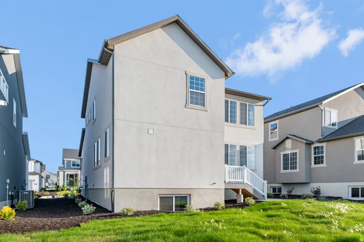 Modern stucco exterior with multiple window styles, including a large basement window