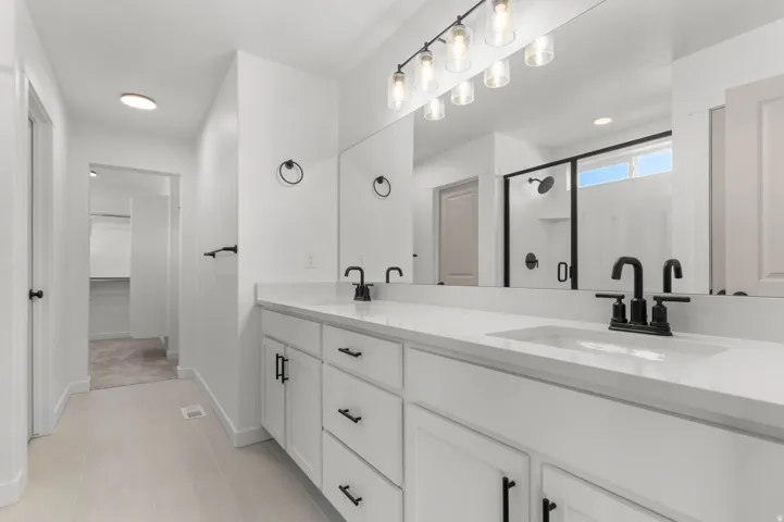 Double vanity with white cabinetry, matte black hardware, and integrated sinks