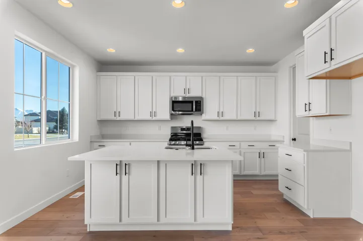 Contemporary kitchen featuring white cabinetry, a central island with a solid surface countertop, stainless steel appliances, and recessed lighting