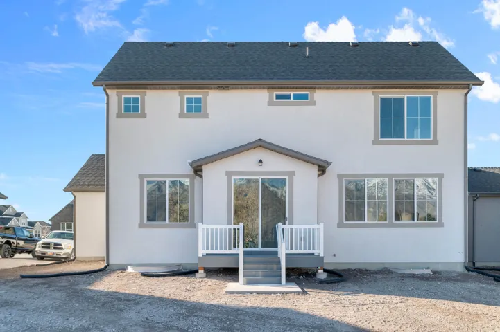 Contemporary rear elevation featuring a neutral stucco finish, multiple windows, and a covered patio with white railing