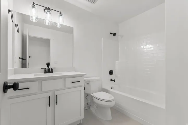 Modern bathroom featuring a white vanity with matte black hardware, a rectangular sink with a matte black faucet, and a large wall-mounted mirror