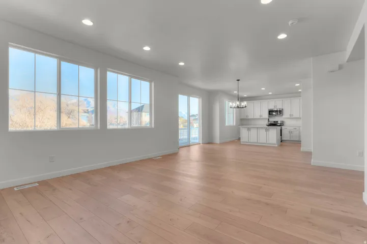 Expansive open-concept living space featuring light wood-finish flooring, recessed lighting, and a modern kitchen