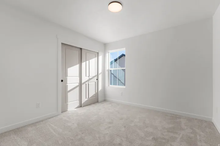 Bright interior space featuring light gray carpeting, crisp white walls, and a recessed ceiling light