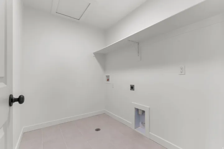Dedicated utility space with durable tile flooring and a functional wall shelf