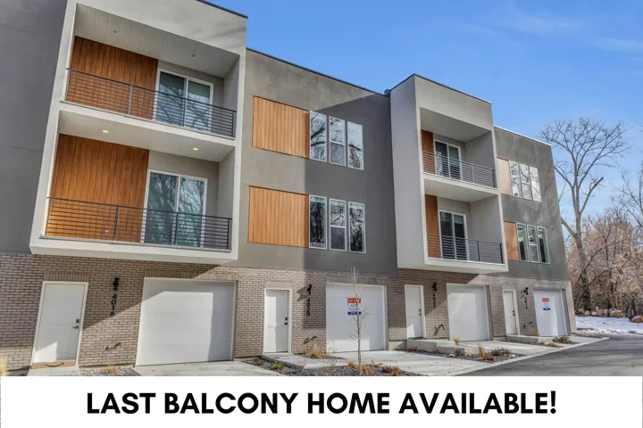 Modern multi-story facade featuring textured gray and light-colored stucco, brick accents, and wood-finish paneling