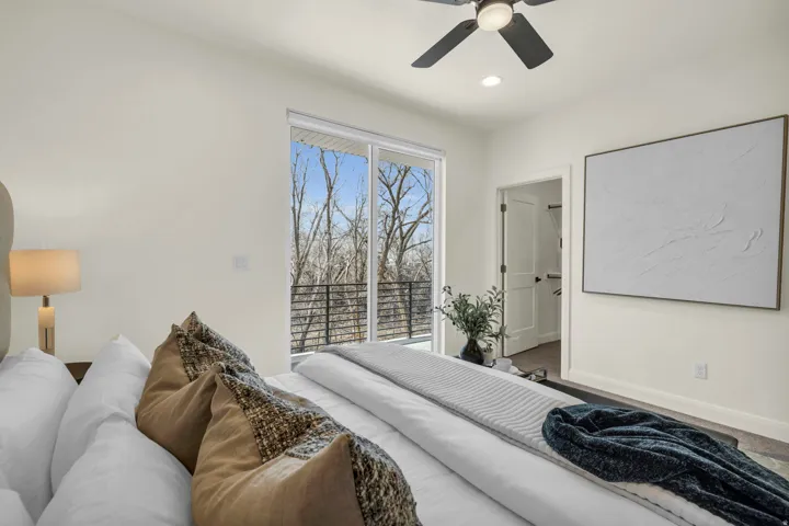 Bedroom with a sliding glass door leading to a balcony with black metal railings, a ceiling fan with integrated lighting, recessed lighting, and a doorway revealing a closet space