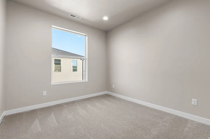 Neutral-toned room featuring a large window, recessed lighting, and light-colored carpeting