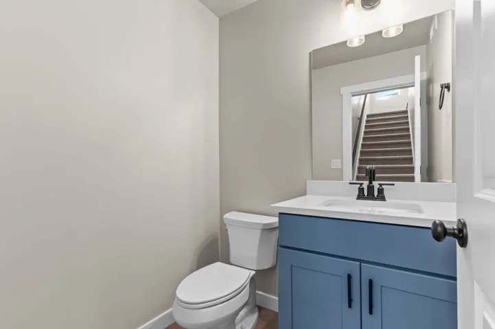 Powder room featuring a blue vanity with a white countertop, an integrated sink, and a wall-mounted mirror