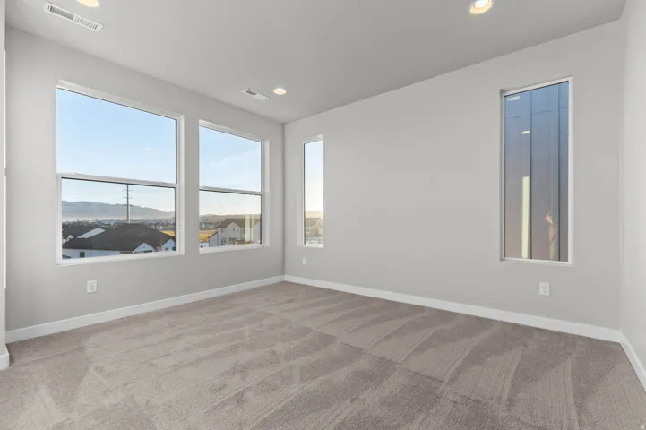 Spacious room with plush carpeting, recessed lighting, and multiple windows offering abundant natural light and distant mountain scenery
