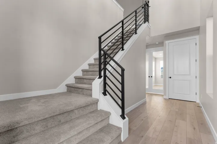 Contemporary staircase with dark metal horizontal railings and light gray carpeted treads