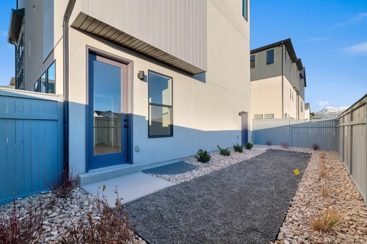Enclosed exterior space featuring a full-light panel door, adjacent window, and a combination of aggregate and stone ground cover