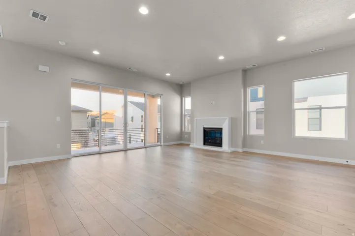 Spacious room featuring light wood-finish flooring, recessed lighting, and a white mantel fireplace