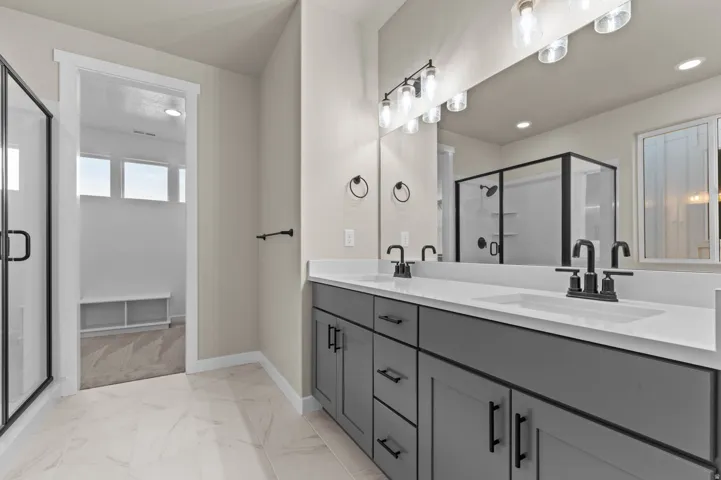 Dual vanity with dark gray cabinetry, white countertops, and matte black fixtures