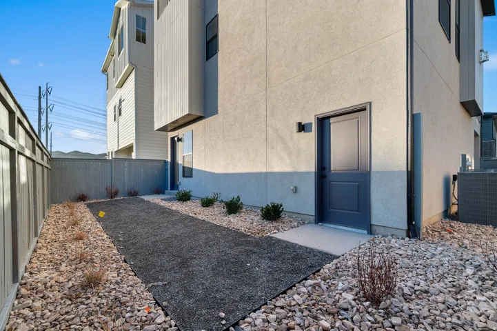 Modern exterior featuring a dark gray entry door, light stucco siding, and a contrasting vertical panel accent