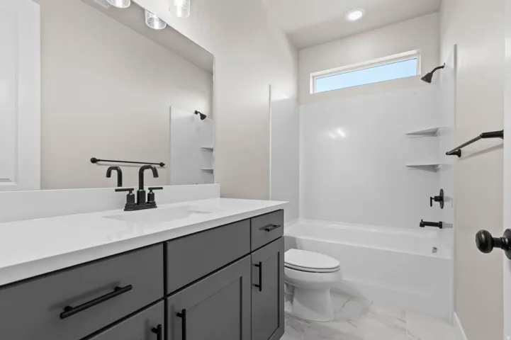 Contemporary bathroom featuring a dark gray vanity with black hardware, a white countertop, and a rectangular undermount sink with a matte black faucet