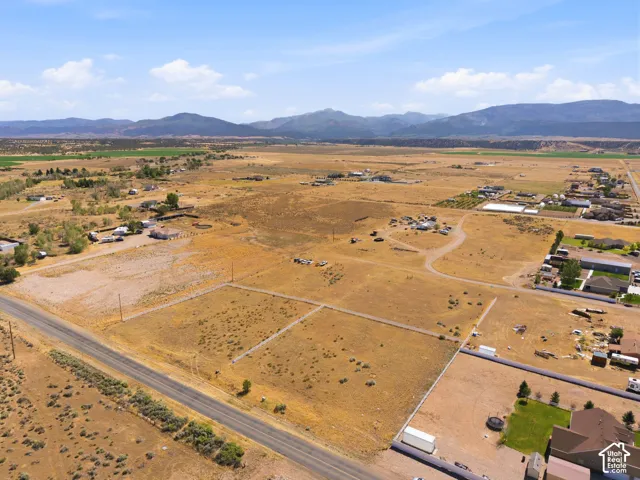 Expansive rural landscape featuring a paved road, scattered residences, and distant mountains