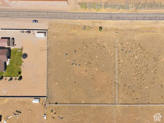 Expansive undeveloped land parcel featuring perimeter fencing, natural ground cover, and direct road frontage
