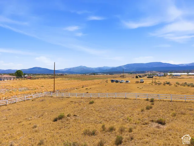Expansive open land with a white perimeter fence, featuring a distant mountain backdrop