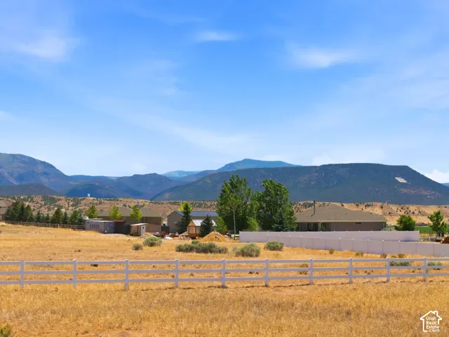 Expansive property featuring a white picket fence, a large open field, and distant mountain ranges