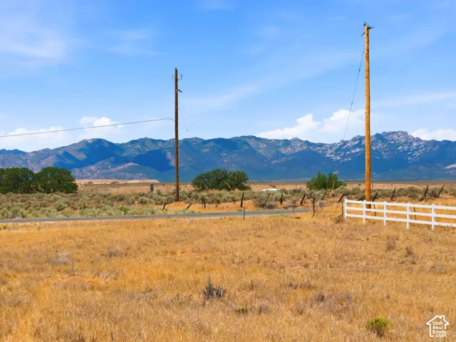 Expansive open field with a white rail fence and distant mountain range