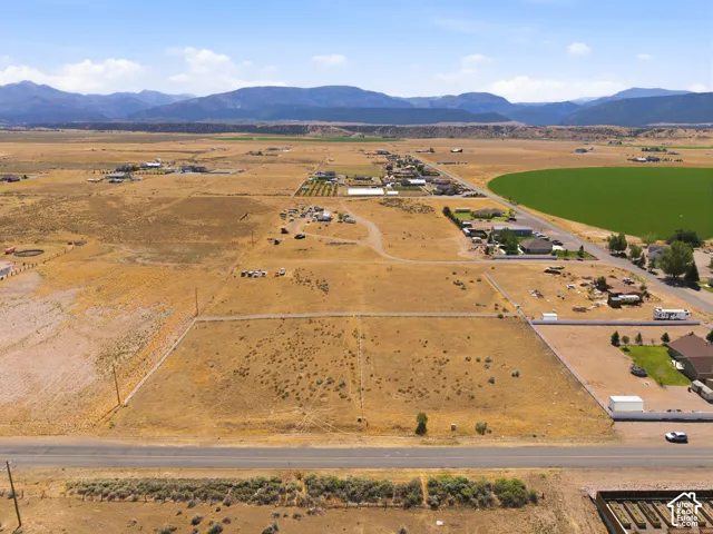 Expansive undeveloped land parcel featuring a clear boundary, direct road frontage, and a distant mountain backdrop