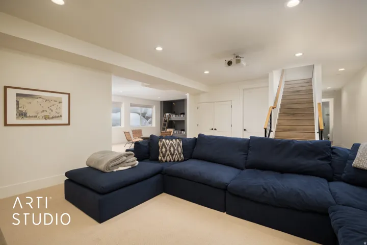 Spacious lower-level area with recessed lighting, light-colored carpeting, and a built-in ceiling projector