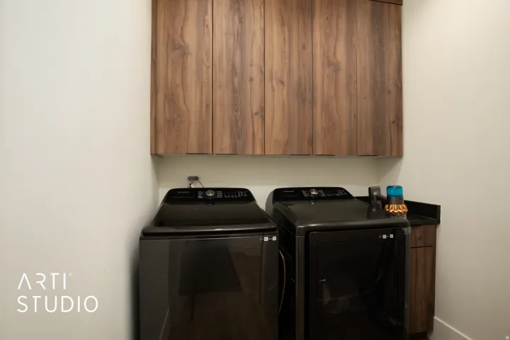 Laundry area featuring wood-finish upper cabinetry with dark hardware