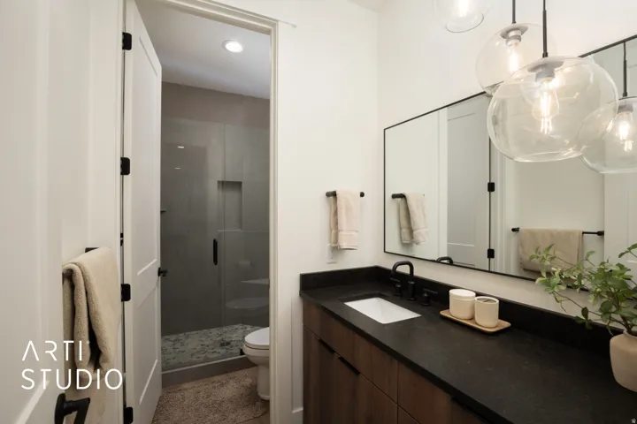 Modern bathroom featuring a wood-finish vanity with a dark countertop, an undermount sink, and matte black fixtures