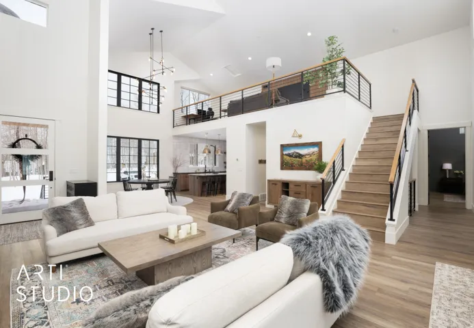 Vaulted great room with expansive wood-finish flooring, a contemporary chandelier, and a second-story balcony