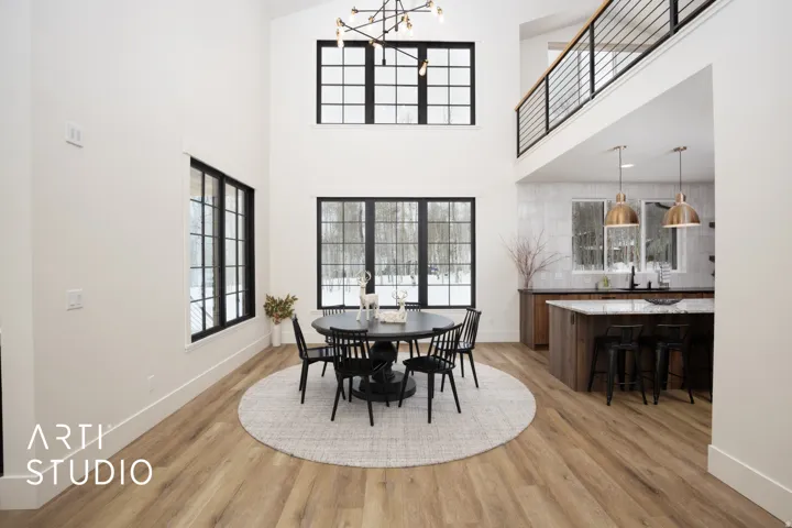 Open-concept living area featuring a two-story ceiling, light wood-finish flooring, and a contemporary chandelier