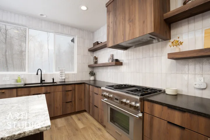Modern kitchen featuring wood-finish cabinetry, dark countertops, and a white subway tile backsplash