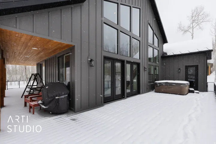 Spacious exterior deck featuring a covered patio with wood-finish ceiling, multiple floor-to-ceiling windows, double French doors, and an integrated outdoor spa