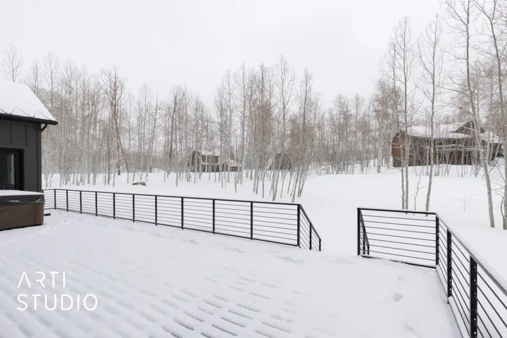 Spacious outdoor deck with modern metal railings, featuring a built-in hot tub