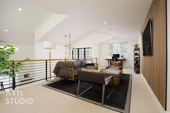 Vaulted ceiling loft space featuring light-toned carpeting and a horizontal slat railing with a wood-finish top rail