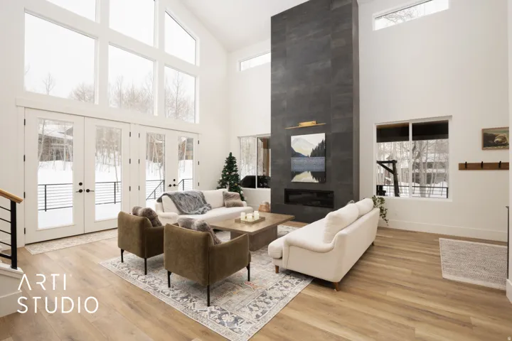 Vaulted ceiling living room featuring a floor-to-ceiling dark tile fireplace with a linear insert, full-height windows, wood-finish flooring, and a contemporary open-tread staircase with metal balusters