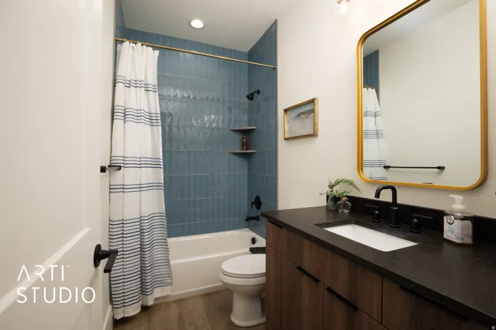 Bathroom featuring a wood-finish vanity with a dark countertop and undermount sink