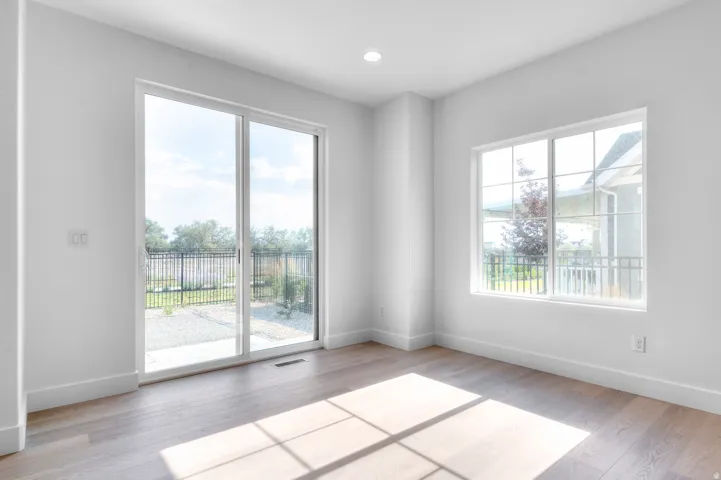 Bright room featuring a large sliding glass door, an additional window with grid panes, recessed ceiling lighting, light wood-finish flooring, and white baseboards