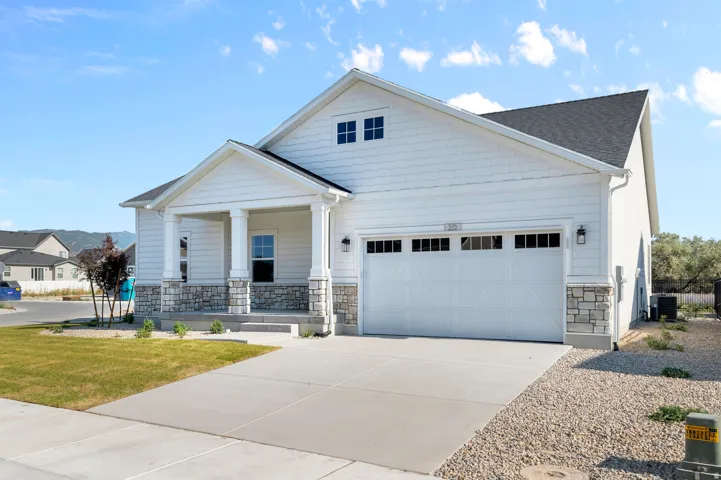 Contemporary ranch-style exterior featuring white siding and a covered front porch with stone-clad columns