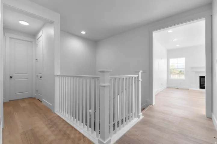 Entry hall featuring light wood-finish flooring, white walls, recessed lighting, and a white balustrade