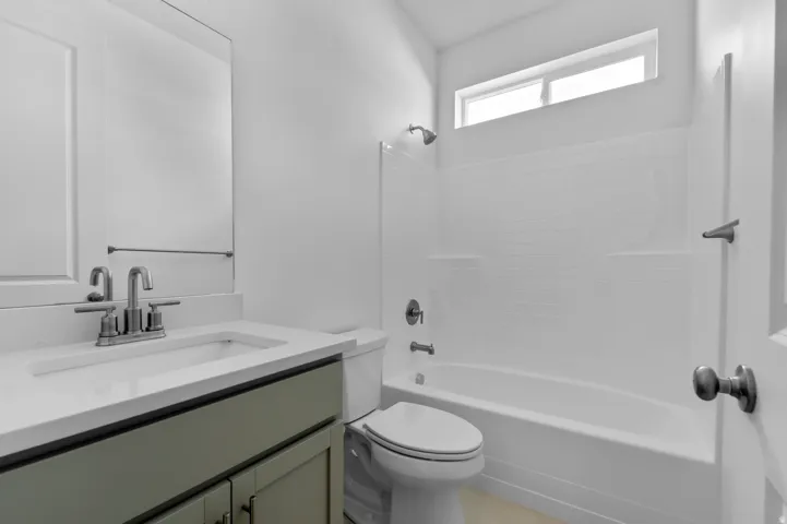 Bathroom featuring a single vanity with a light green cabinet base, a white countertop, and a rectangular sink